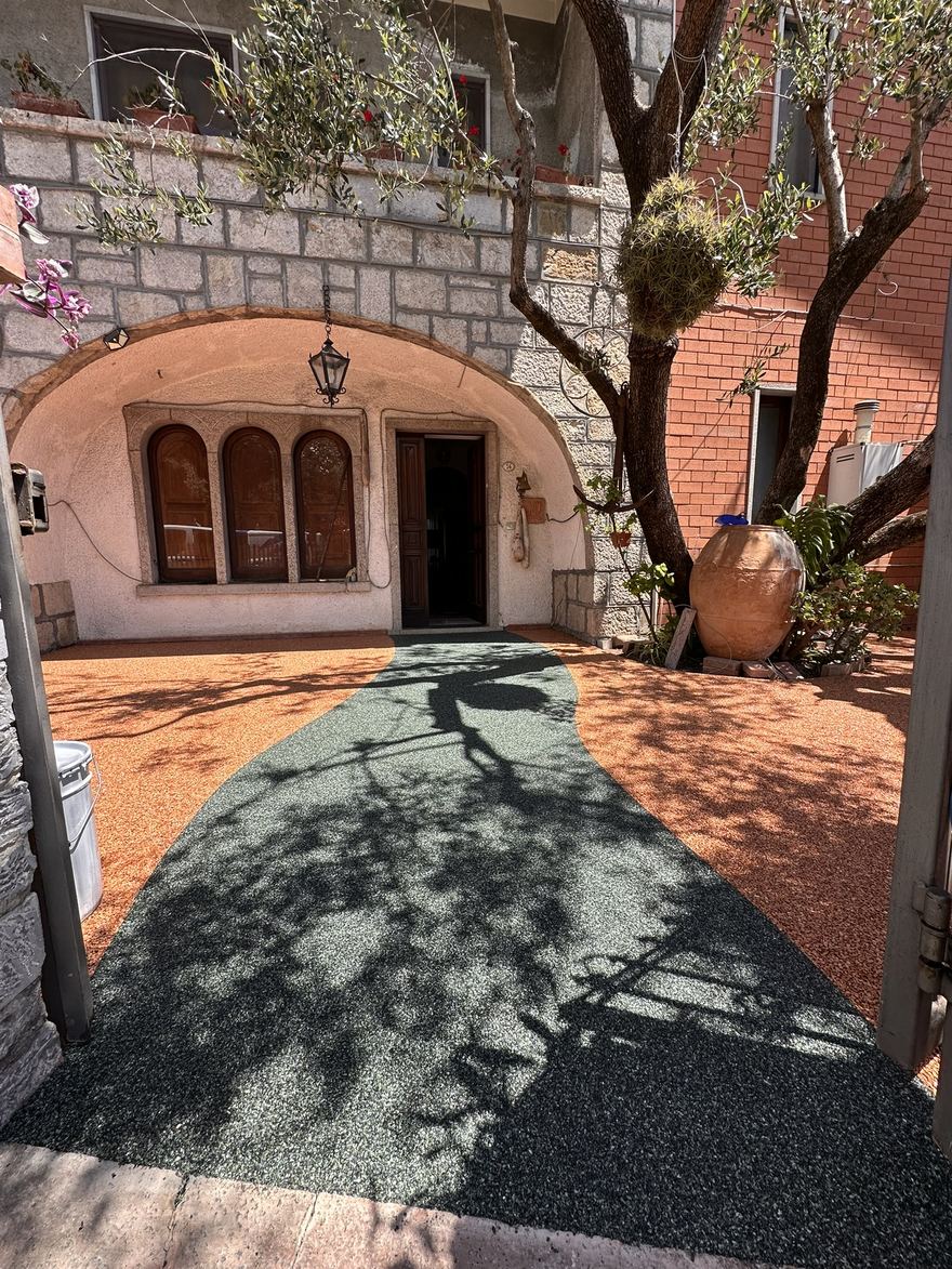 Cortile privato nel Cilento con pavimentazione drenante in resina bicolore, camminamento verde e fondo color cotto, posata da Edil Lenza sul pavimento esistente